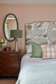 Romantic bedroom showcasing the Carnival Olive headboard with a botanical print of leaves and pomegranates. Designed by Natalie Davies Interior Design, the room embodies a traditional cottage style with soft tones and vintage-inspired furnishings. Photography by Chris Snook.